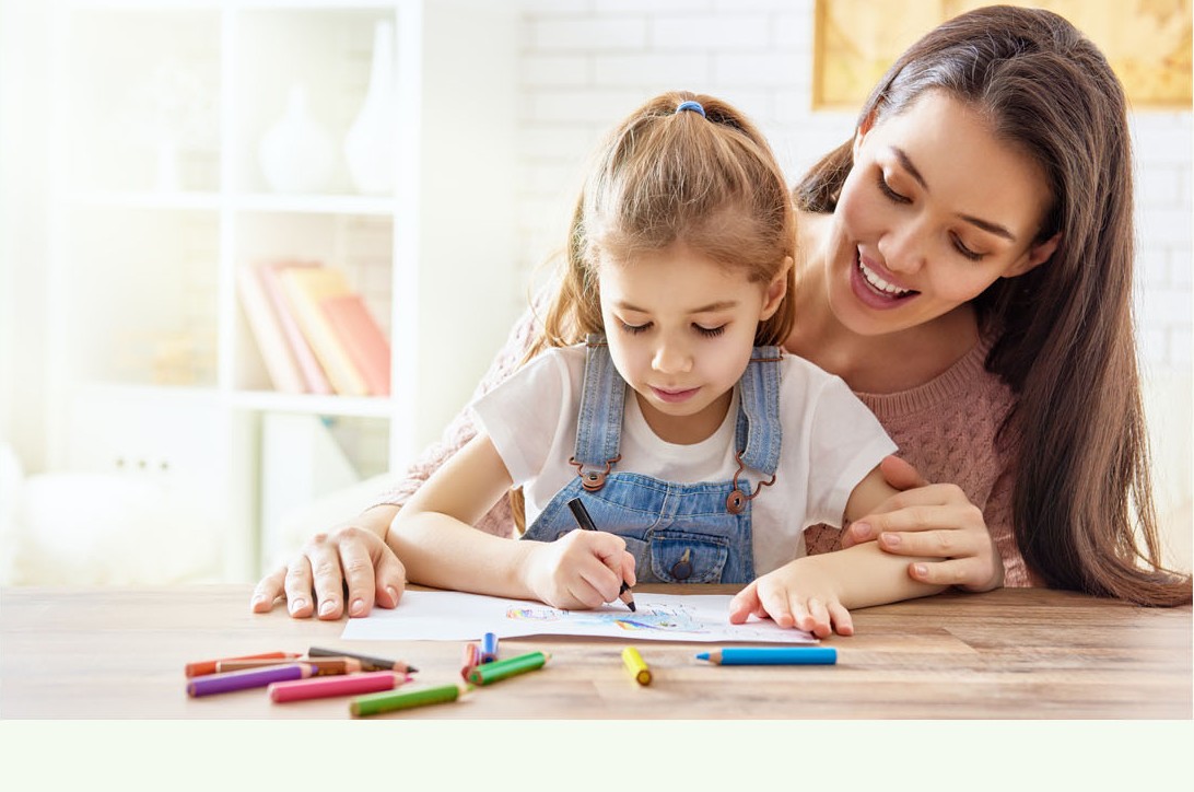 Parent helping a child draw at a table